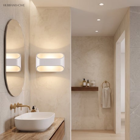 Two white oval sconces lit beside a bathroom mirror and basin