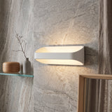 White oval sconce lighting a marble wall above and below