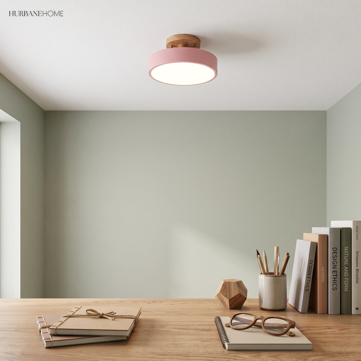 Pink macaron wood ceiling light above a study desk with a sage green wall