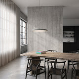 Grey LED disc pendant over a rustic wood dining table in a concrete loft