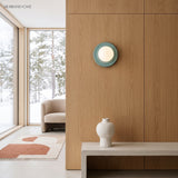 Blue orb wall sconce mounted flush on an oak-panelled wall in a bright room