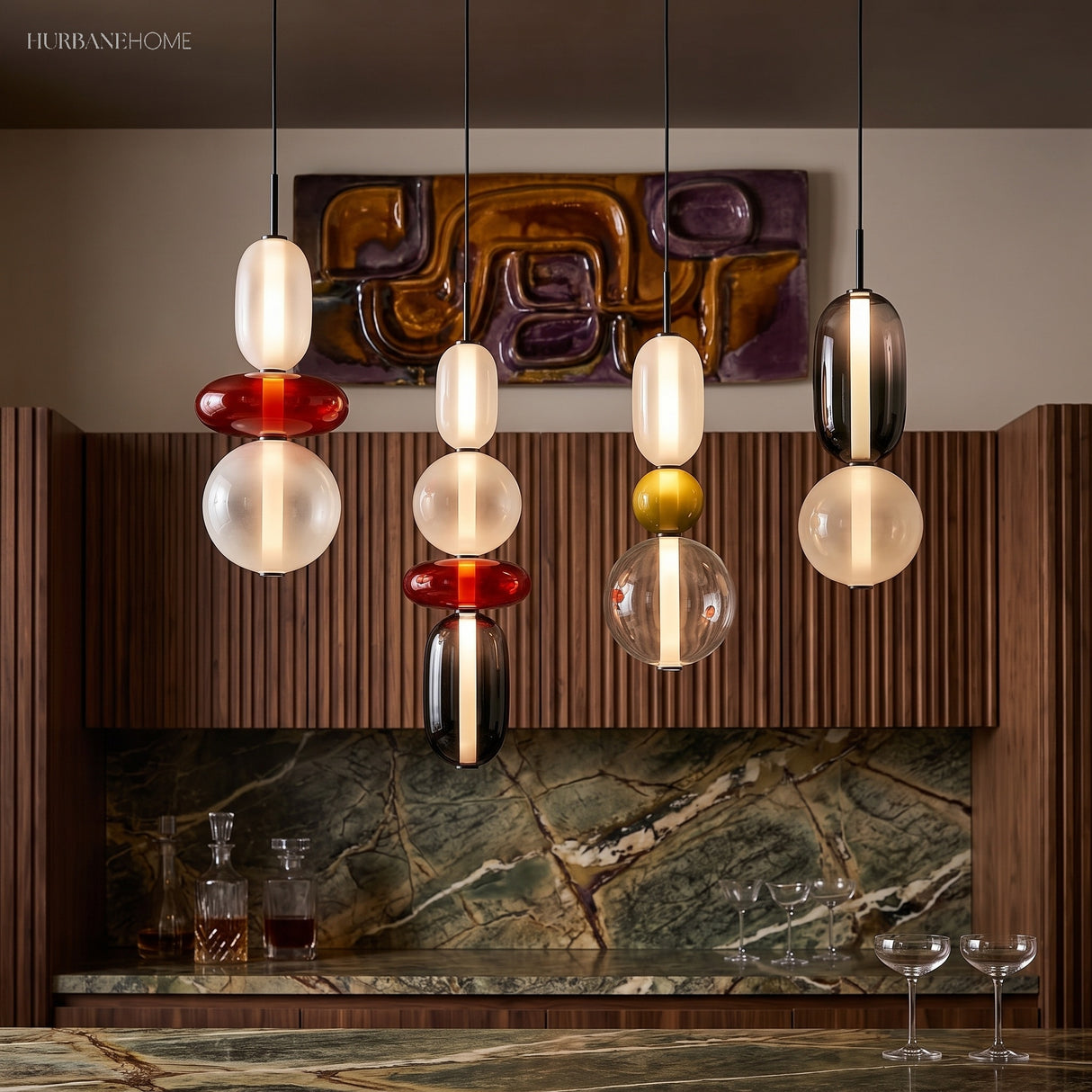 Four colorful glass pendant lights in a row above a marble bar counter