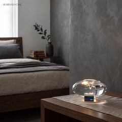 Glowing oval glass lamp on a bedroom nightstand near a bed