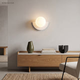 White glass globe wall sconce above a wood sideboard in a living room