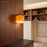 Amber glass wall sconce glowing on walnut panelling beside a filled bookcase