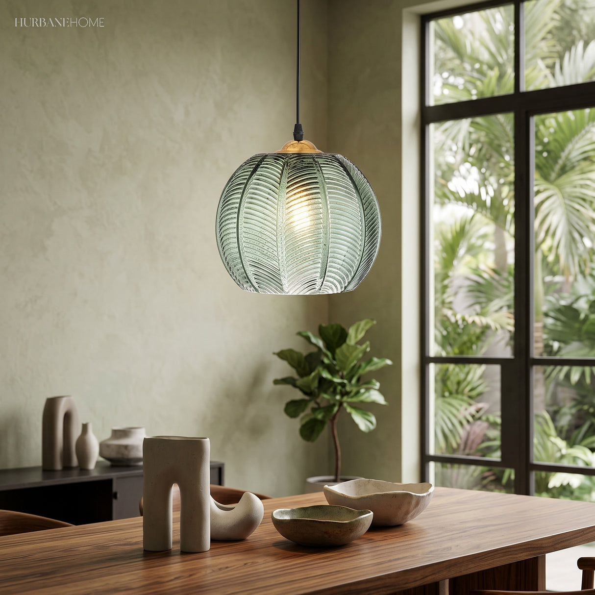 Lit green glass globe pendant above a wooden dining table beside a garden window