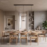 Two black disc pendants glowing over a light oak dining table set for dinner