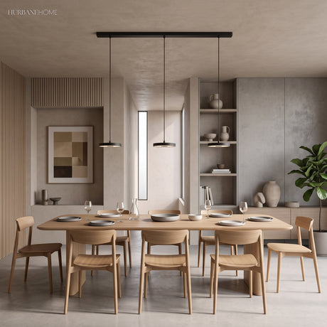 Two black disc pendants glowing over a light oak dining table set for dinner