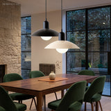 Two dome pendant lights above a walnut dining table with green velvet chairs