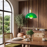 Green glass bowl pendant light above a wooden dining table set for a meal