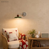 Beige disc swing arm wall lamp glowing warmly above a rattan armchair