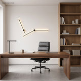 Two black linear wall lights forming an angled line above a walnut office desk