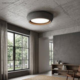 Dark grey round ceiling light on an exposed concrete slab in an industrial room