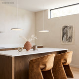 Two white disc pendant lights above a white kitchen island with terracotta bar stools