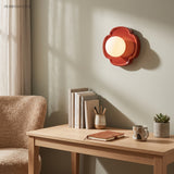 Red flower base wall light glowing above an oak study desk with books