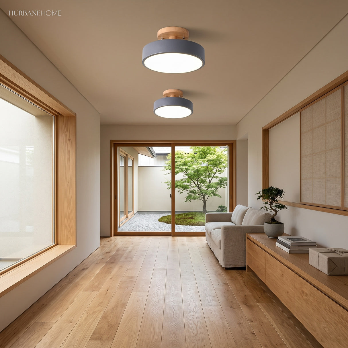 Two gray round ceiling lights lighting a bright wood-floored hallway near a garden