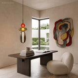 Red and amber stacked glass pendant light glowing over a dark wood desk