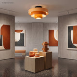 Orange tiered ceiling light glowing in a concrete art gallery room