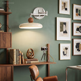 Cream swing arm wall sconce on green wall beside framed abstract art