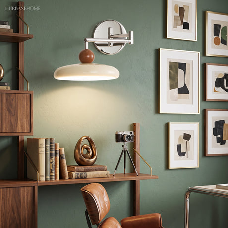 Cream swing arm wall sconce on green wall beside framed abstract art