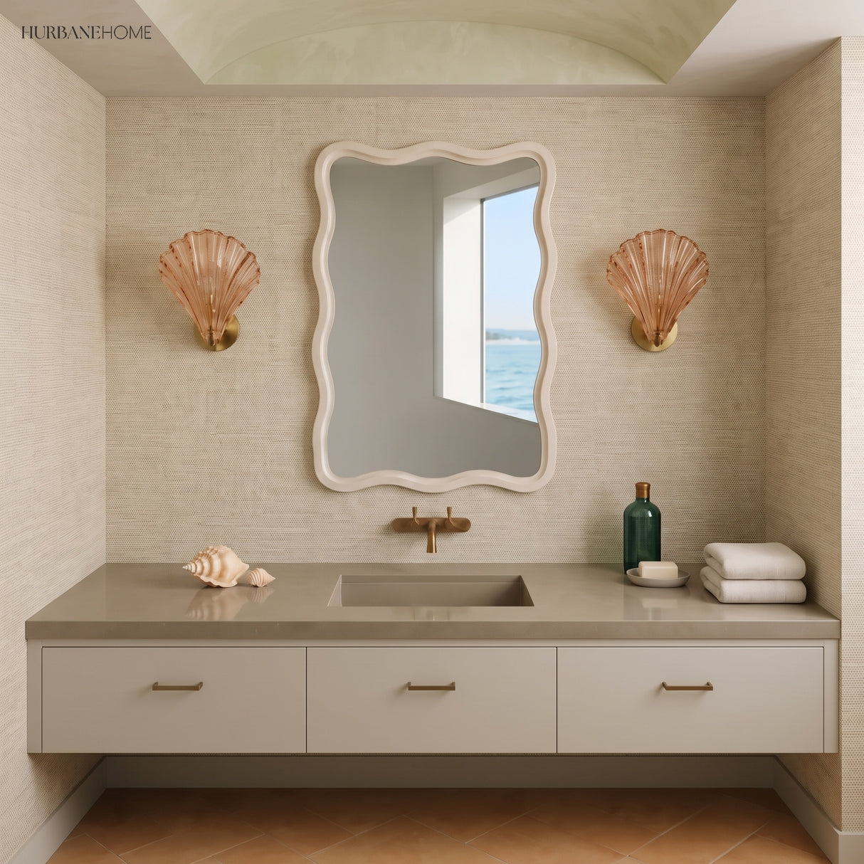 Two amber shell sconces beside a wavy mirror over a neutral bathroom vanity
