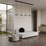 Two minimalist pendant discs hanging above a pale wood table in a modern room
