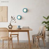Two blue orb wall sconces above a dining table with rattan chairs