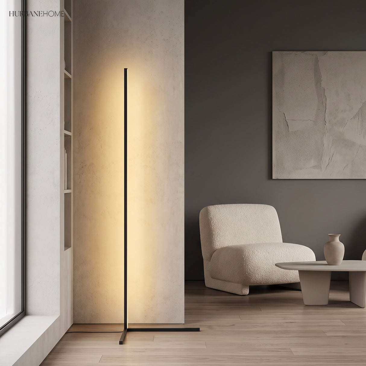 Black minimalist LED floor lamp lighting a corner near a boucle chair and framed art