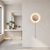 Stone wall sconce with pull-cord glowing in a bright minimalist interior