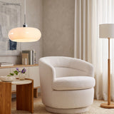 White glass pendant light beside a boucle armchair and floor lamp in a lounge