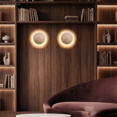 Pair of travertine wall sconces on a warm timber wall above a lounge chair