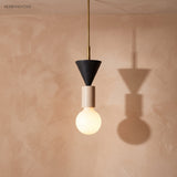 Black cone and wood pendant light with a glowing globe bulb on a terracotta wall