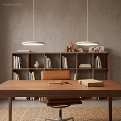 Pair of white pendant lights hanging above a walnut desk and open bookshelf