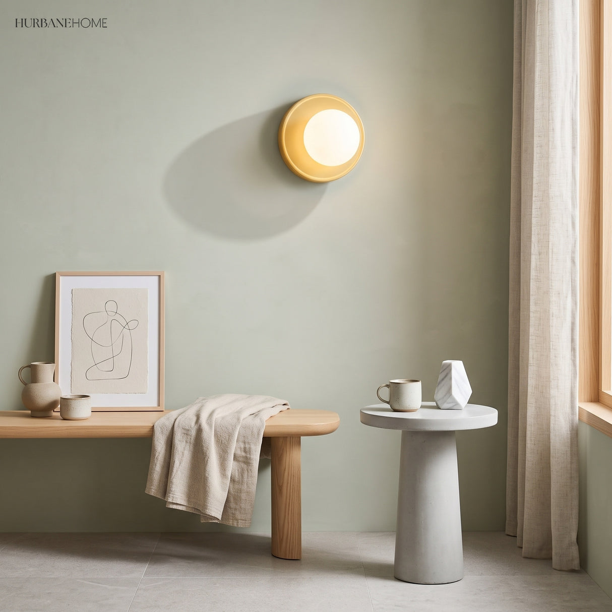 Yellow orb wall sconce glowing warm on a sage green wall above a bench