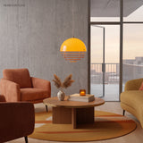 Orange glass dome pendant glowing above a wood coffee table in a warm living room