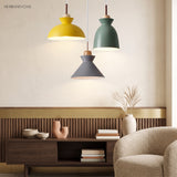 Yellow, green and grey pendant lights grouped above a walnut sideboard and armchair