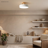 White flush mount ceiling light glowing warmly in a calm neutral living room