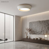 White cement ceiling light in a calm Japandi space beside a glass rock garden