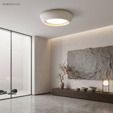 White cement ceiling light in a calm Japandi space beside a glass rock garden