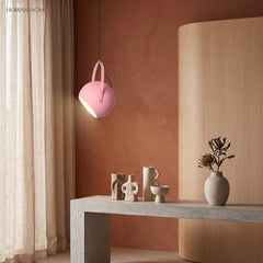 Rose pink ball pendant light tilted against a warm terracotta plaster wall