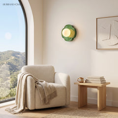 Green glass globe wall sconce in a sunny reading nook with boucle chair