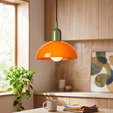 Orange glass bowl pendant light hanging over a light wood kitchen counter