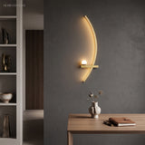 Gold arc wall light with frosted acrylic globe beside a wooden desk