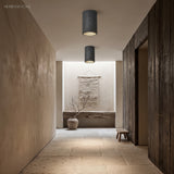 Two black composite surface-mount ceiling lights over a stone-floored hallway