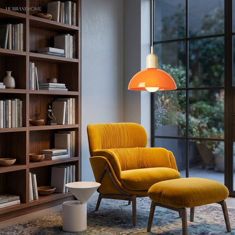 Orange bowl pendant light glowing above a mustard reading chair and shelves