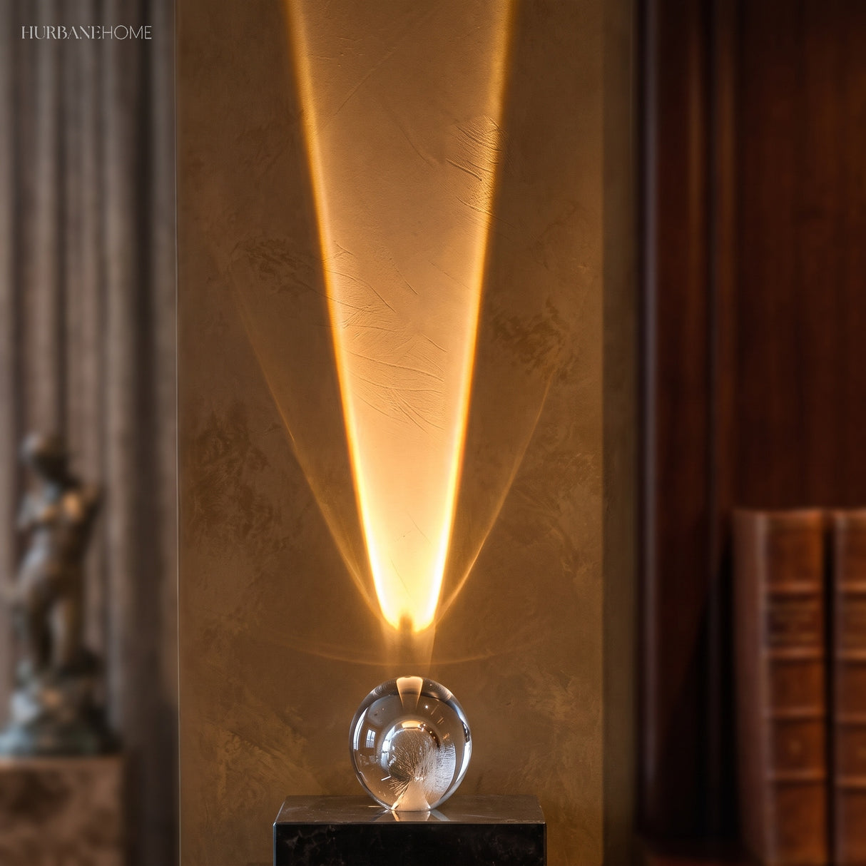Clear glass mood lamp throwing a warm beam up a plaster wall