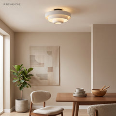 White tiered ceiling light above a walnut dining table and boucle chair