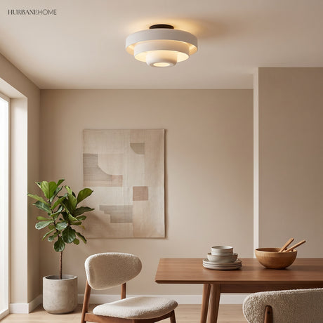 White tiered ceiling light above a walnut dining table and boucle chair