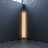 Warm LED glow reflecting off two dark walls from a slim black corner floor lamp