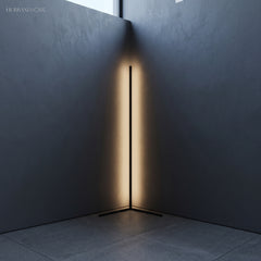 Warm LED glow reflecting off two dark walls from a slim black corner floor lamp